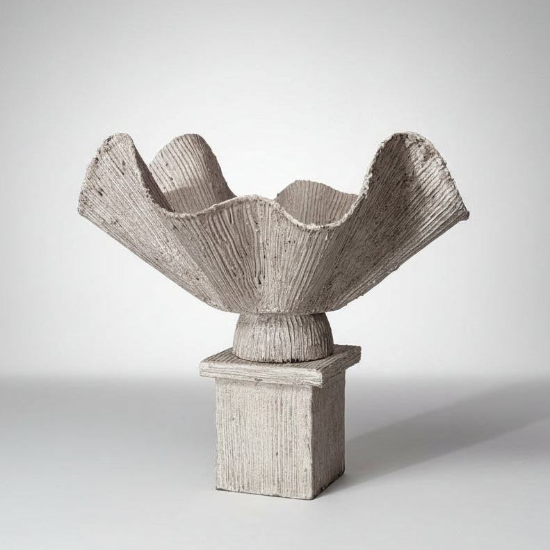 Ceramic sculpture with a textured, fan-like top and square base on a marble surface.